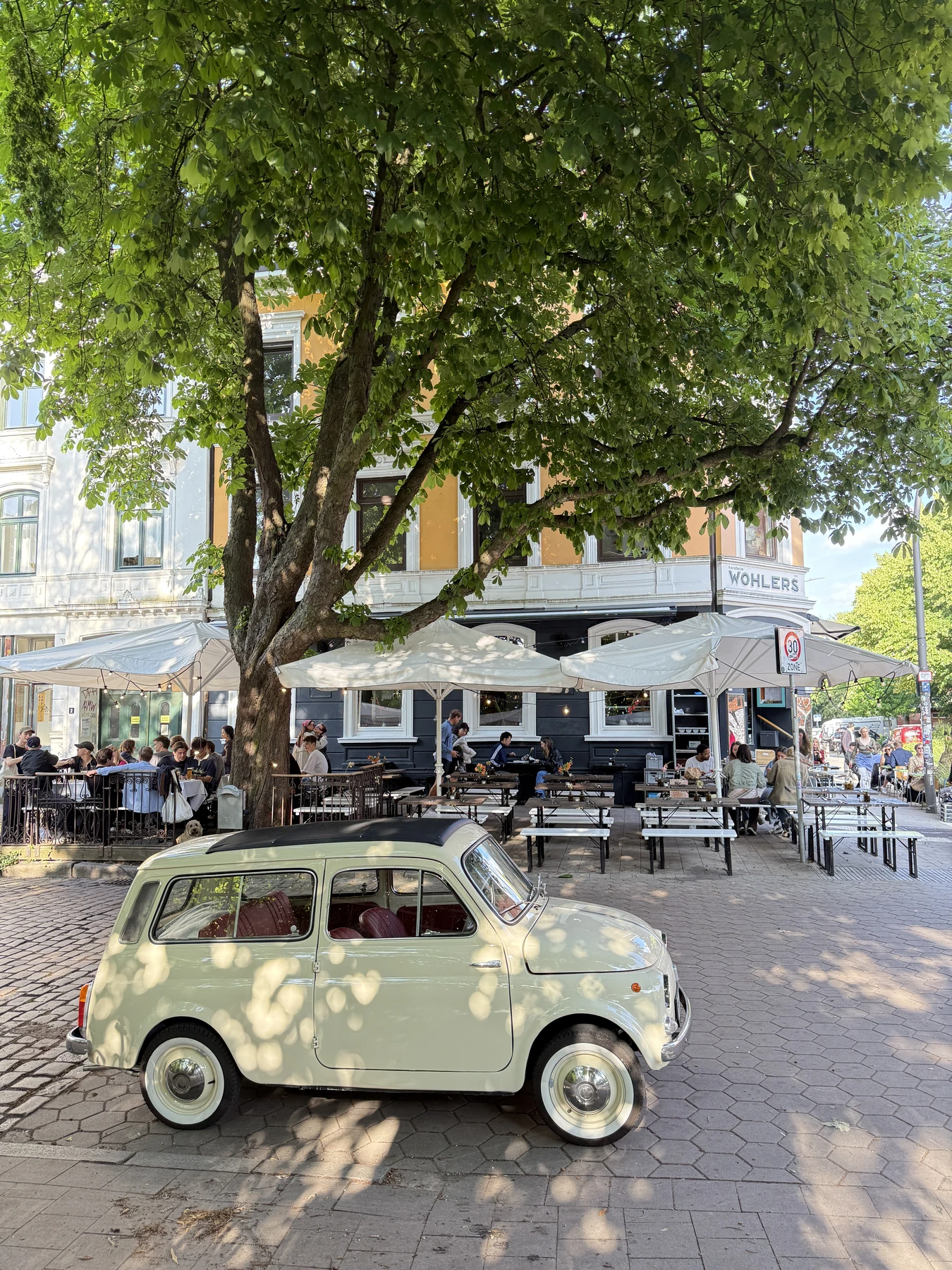 WOHLERS mit großer Terrasse unter der Kastanie und historischem Kleinwagen im Vordergrund